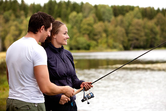 A man showing a woman how to fish