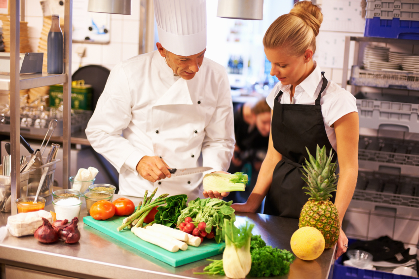 Portrait of experienced chef giving culinary lessons to female trainees