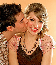 Young man kissing woman on cheek, smiling, portrait